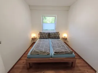 Ein einfaches Schlafzimmer mit zwei Betten und entspannter Atmosphäre. Das Zimmer hat einen kleinen Fensterblick und stilvolle Nachttischlampen.