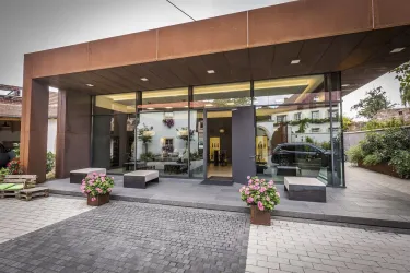 Ein modernes Gebäude mit großen Glasfenstern und einer einladenden Eingangsbereich. Vor dem Eingang stehen Blumenkübel mit bunten Pflanzen.