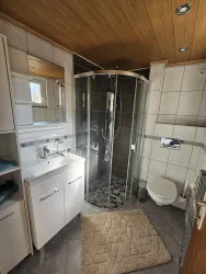 Ein modernes Badezimmer mit einer Glasdusche und einer weißen Toilette. Die Wände sind gefliest und es gibt einen geschmackvollen Teppich auf dem Boden.