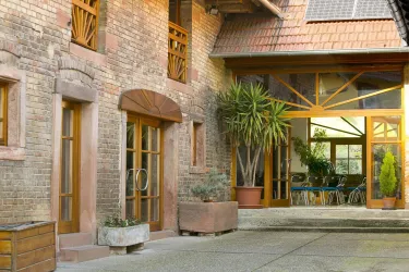 Ein schöner Innenhof mit Backsteinwänden und großen Fenstern. Die Pflanzen und das Holzdesign schaffen eine einladende Atmosphäre.