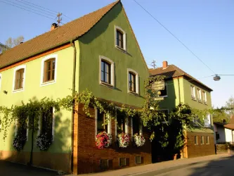 Hausansicht des Weinguts und Gasthaus Nägle mit grüner Fassade und Weinranken entlang des Gebäudes.