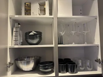 Eine Küchenzeile mit verschiedenen Geschirrstücken. Auf den Regalen sind Schalen, Gläser und Tassen in einem modernen Design angeordnet.