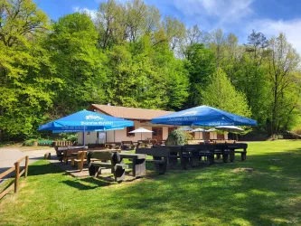 Ein gemütliches Restaurant im Grünen mit großen Sonnenschirmen. Es gibt viele Sitzgelegenheiten auf der Wiese.