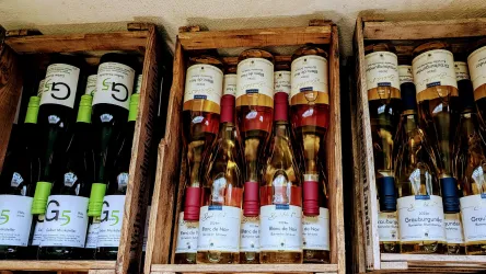 Kisten mit verschiedenen Weinsorten in Flaschen sind ordentlich gestapelt. Die Etiketten sind deutlich sichtbar und zeigen eine Vielfalt an Weinen.