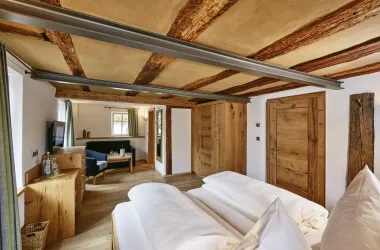 Ein gemütliches Zimmer mit zwei Betten und Holzelementen. Helle Farben und viel Tageslicht schaffen eine einladende Atmosphäre.