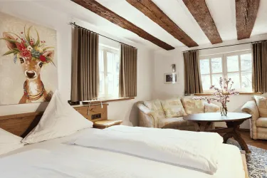 Ein gemütliches Schlafzimmer mit einem großen Bett und einem schönen Gemälde eines Rehs an der Wand. Die Einrichtung ist warm und einladend, mit einem Blick auf das Wohnzimmerbereich.