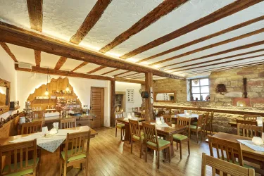Ein gemütliches Restaurant mit Holzdecken und rustikalen Tischen. Die warmen Farben schaffen eine einladende Atmosphäre.