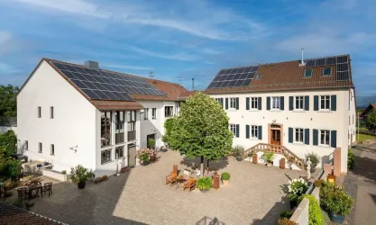Ein modernes Gebäudeensemble mit Solarpanels und einem begrünten Innenhof. Die Architektur verbindet traditionelles Design mit nachhaltiger Technologie.