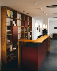 Ein moderner Empfangsbereich mit einem Holzbar und einer offenen Regaleinheit. Die Beleuchtung ist sanft und schafft eine einladende Atmosphäre.