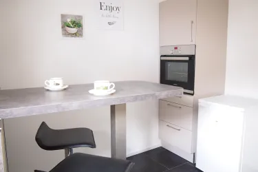 Eine moderne Küche mit einem kleinen Tisch und zwei Tassen. Der Raum hat helle Wände und eine elegante Einrichtung.