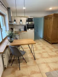 Eine moderne Küche mit einem Holztisch und Stühlen. Im Hintergrund befindet sich ein Holzkasten und elegante Küchenmöbel.