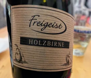 Eine Flasche mit dem Etikett "Freigeist Holzbirne". Das Design ist einfach und zeigt stilisierte Birnenillustrationen.