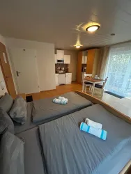 Ein modernes Apartment mit Doppelbett und einer kleinen Küchenzeile. Helle Farben und viel Tageslicht schaffen eine einladende Atmosphäre.