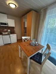 Eine helle Küche mit einem Esstisch und Stühlen. Das Apartment hat moderne Möbel und große Fenster, die viel Licht hereinlassen.