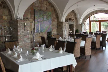 Ein elegantes Restaurant mit Steinmauern und geschmackvoll gedeckten Tischen. Die Atmosphäre ist einladend und gemütlich.