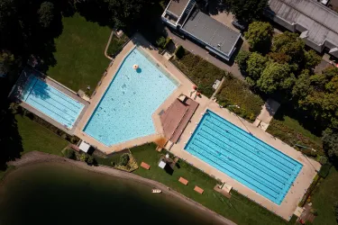 Ein Schwimmbad mit drei Becken, umgeben von Grünflächen. Die Pools sind klar und einladend in der sonnigen Umgebung.