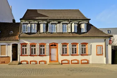 Ein charmantes Haus mit orangefarbenen Fenstern und einem Dach mit Giebel. Die Fassade strahlt eine gemütliche Atmosphäre aus.
