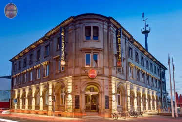 Ein historisches Gebäude mit einer einladenden Fassade und sanfter Beleuchtung. Es gibt Fahrräder vor dem Eingang und Werbeschilder für ein Restaurant.