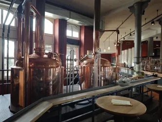 Eine moderne Brauerei mit glänzenden Kupferkesseln und großen Fenstern. Der Raum hat eine einladende Atmosphäre mit Holz- und Metallelementen.