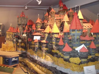 Eine detaillierte Modellstadt mit hohen Burgen und roten Dächern ist zu sehen. Die Landschaft ist künstlich gestaltet und zeigt verschiedene Höhenlagen.