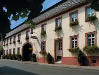 Ein traditionelles Gebäude mit blühenden Fenstern und einem roten Rahmen. Die Straße vor dem Haus ist ruhig und von Bäumen gesäumt.