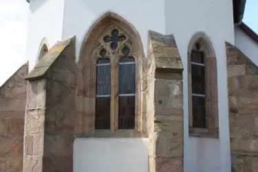 Ein historisches Gebäude mit einer weißen Fassade und gotischen Fenstern. Die Architektur hat markante Steinelemente und lässt auf eine lange Geschichte schließen.