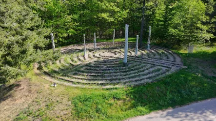 Ein schöner Labyrinth aus Steinen, umgeben von Bäumen. Die klare Anordnung der Spiralen lädt zum Verweilen und Nachdenken ein.