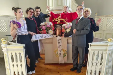 Sechs Schauspieler des Theaterstücks "Kalter weißer Mann" in Aktion vor dem Altar einer Kirche