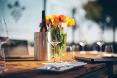 Ein eleganter Tisch mit Gläsern und einem Weinkühler. Im Hintergrund stehen fröhliche Tulpen und der Himmel ist klar.