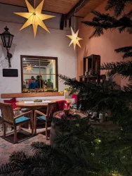 Ein gemütlicher Raum mit einem Holzschreibtisch und Weihnachtssternen an der Decke. Im Hintergrund ist ein Spiegel und Weihnachtsdekoration sichtbar.