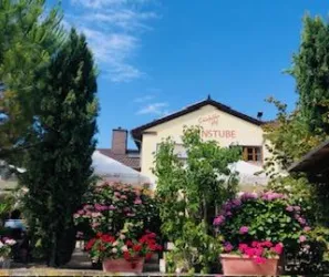Ein gemütliches Restaurant mit blühenden Pflanzen und Bäumen. Der Himmel ist blau und die Atmosphäre ist einladend.