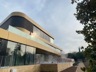 Ein modernes Haus mit einer geschwungenen Fassade und großen Fenstern. Der Garten ist gepflegt und es gibt eine ruhige Atmosphäre.