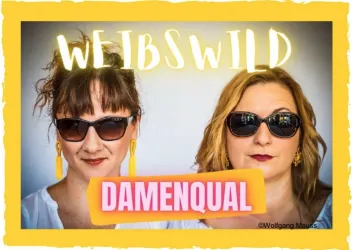 Zwei Frauen mit Sonnenbrillen posieren für ein Foto. Der Hintergrund zeigt den Schriftzug „WEIBSWILD“ und „DAMENQUAL“.