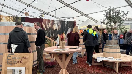 Eine belebte Messe mit vielen Besuchern, die sich unterhalten. Stände und Aussteller sind im Hintergrund sichtbar.