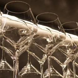 Eine Reihe von eleganten Weingläsern steht auf einem Tisch. Die Gläser reflektieren das Licht und kreieren eine ansprechende Atmosphäre.