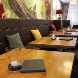 Ein gemütliches Restaurant mit Holz- und Ledermöbeln. An den Wänden sieht man eine dekorative Weingemälde.