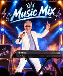 Ein Musiker steht am Keyboard und singt auf der Bühne. Im Hintergrund leuchtet das Banner „Music Mix“ mit bunten Lichtern.