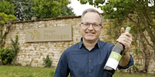 Ein Holzfass mit einem kleinen Stück Käse darauf. Im Hintergrund sind weitere Holzfässer sichtbar.