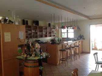 Eine gemütliche Bar mit Holzregalen und vielen Getränken. Helle Räume und Sitzplätze laden zum Verweilen ein.