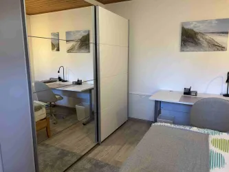 Ein moderner Raum mit zwei Arbeitsbereichen. Der Raum ist hell und minimalistisch eingerichtet.