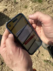 Eine Person hält ein Smartphone in den Händen. Auf dem Bildschirm ist eine Nachricht zu sehen.