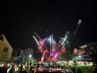 Menschen schauen fasziniert zu einem Feuerwerk am Nachthimmel. Bunte Lichter erleuchten die Dunkelheit.