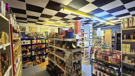 Ein geschäftiger Laden mit Regalen voller Duft- und Räucherstäbchenartikeln. Die Wände sind mit bunten Produkten dekoriert und die Decke hat ein Schachbrettmuster.