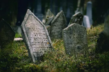 Ein alter Friedhof mit schiefen Grabsteinen, umgeben von Gras. Die Atmosphäre wirkt ruhig und melancholisch.