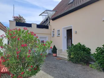 Ein schöner Eingang mit blühenden Pflanzen und einem modernen Haus. Die Terrasse ist hell und einladend.