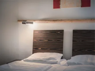 Ein gemütliches Schlafzimmer mit zwei Betten und modernen Kopfplatten. Die Beleuchtung ist dezent und schafft eine entspannte Atmosphäre.