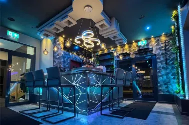 Eine stilvolle Bar mit modernen Lichtakzenten und eleganten Stühlen. Die Atmosphäre ist einladend und gemütlich.