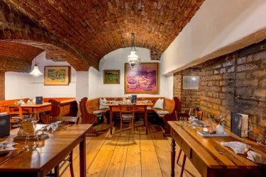 Ein gemütliches Restaurant mit einem Ziegelgewölbe. Holztafeln und Kunstwerke schaffen eine einladende Atmosphäre.