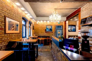 Ein gemütliches Café mit Holz- und Ziegelwänden. Eine elegante Deckenleuchte sorgt für eine warme Atmosphäre.