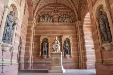 Ein prächtiger Innenraum mit einer Statue in der Mitte und zwei beeindruckenden Skulpturen an den Seiten. Die Wände sind in warmen Farbtönen mit detaillierten Verzierungen gestaltet.
